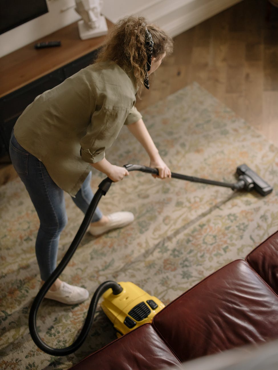 woman in beige long sleeve shirt and maroon pants holding vacuum cleaner